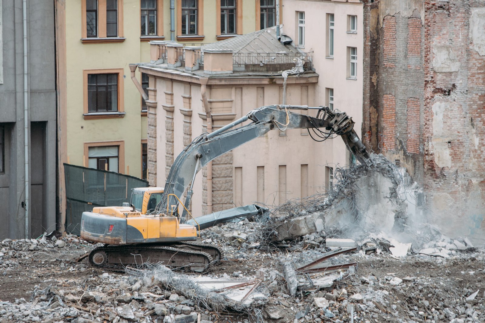 Building of the former hotel demolition for new construction, using a special hydraulic excavator-destroyer. Complete highly mechanized demolition of building structures. Construction site concept
